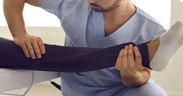Physical therapist stretching patient leg